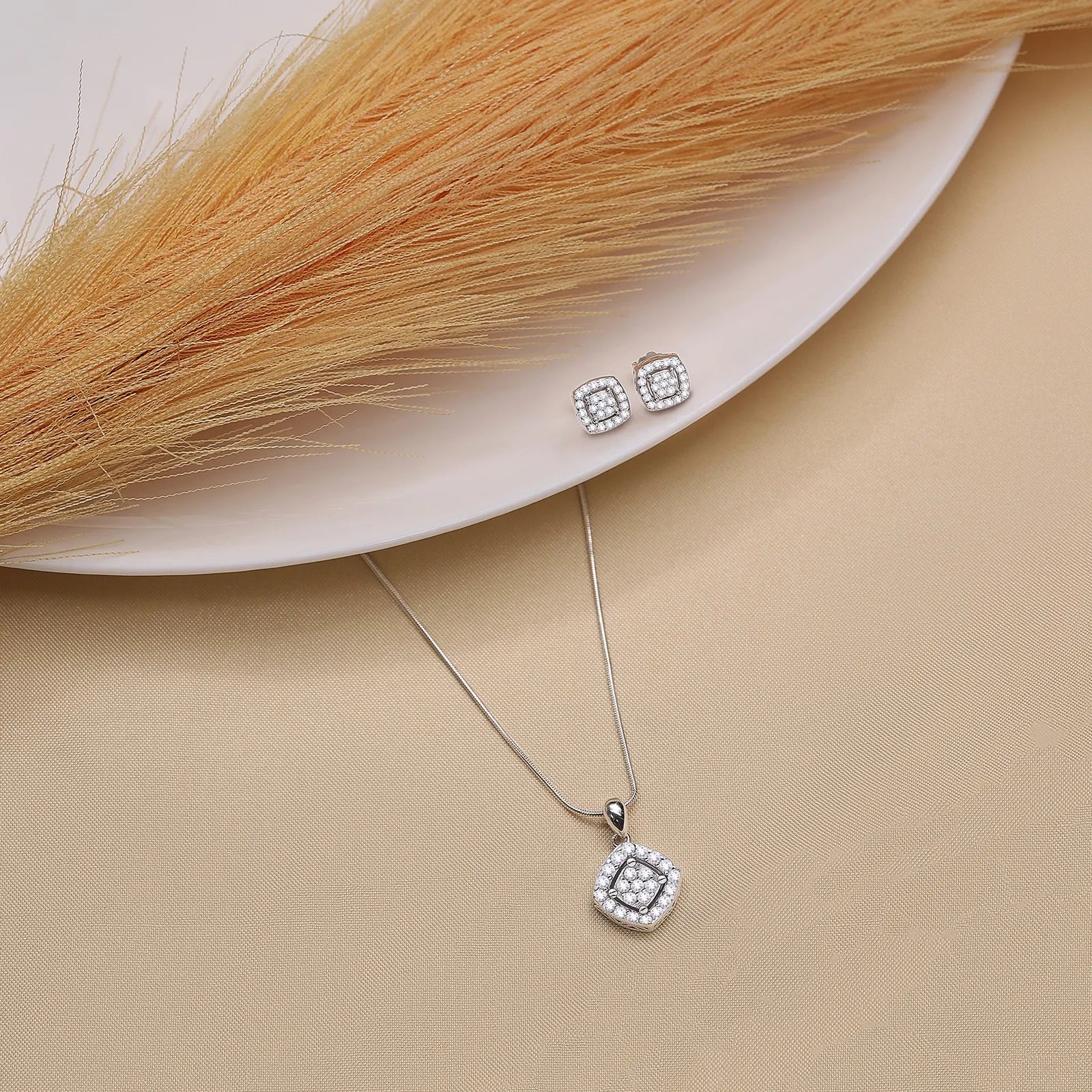 This is a silver-toned cushion-cut crystal pendant necklace with cubic zirconia and matching stud earrings