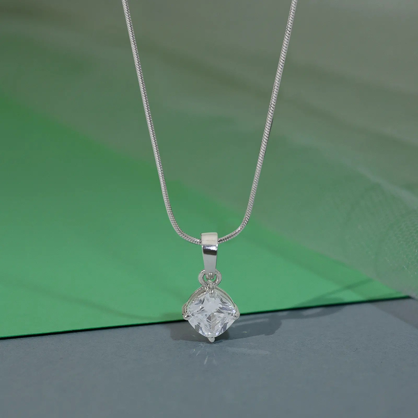 This is a silver-tone necklace with a square-cut white topaz or cubic zirconia crystal pendant